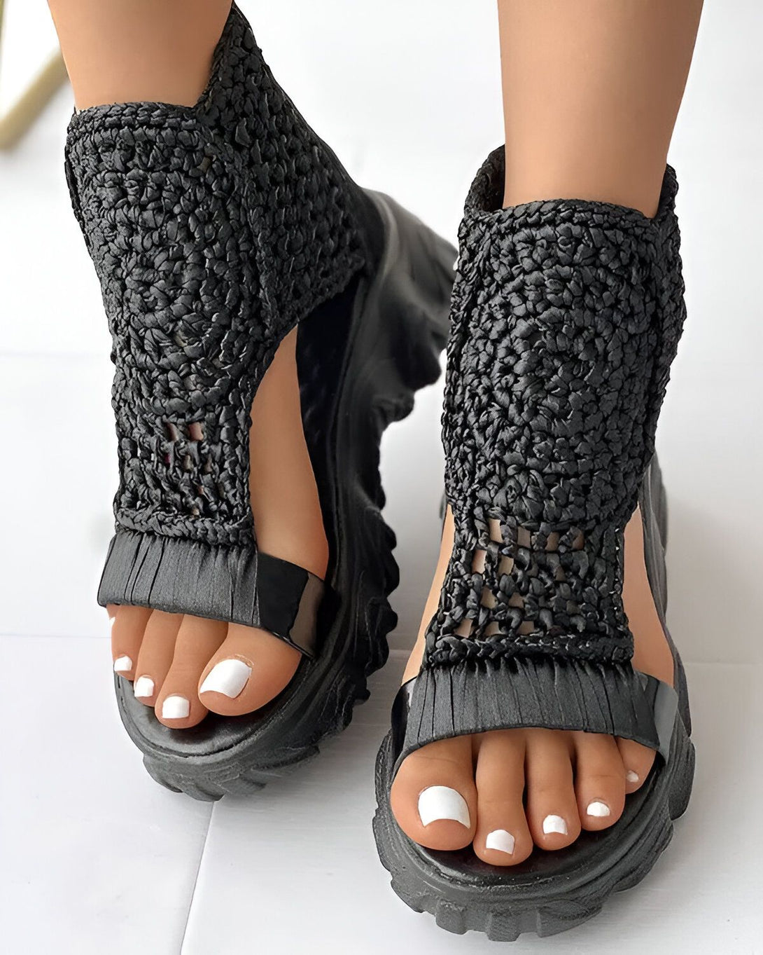 Une paire de sandales noires à talons compensés avec des lanières tressées sur le dessus.
