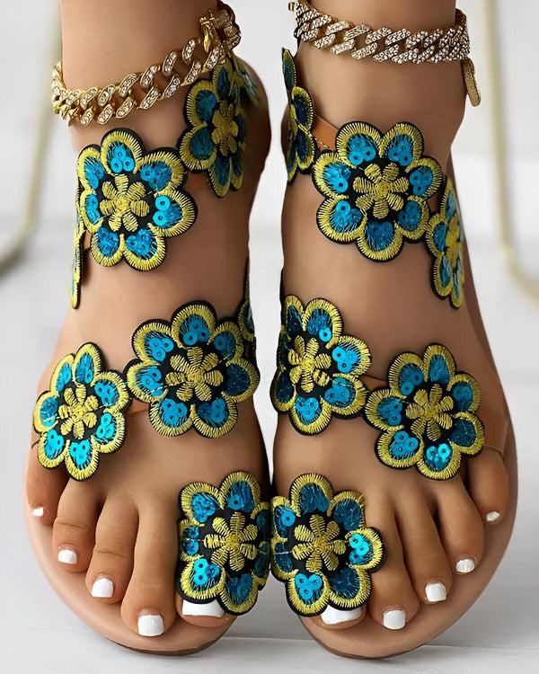 Une paire de sandales plates faites à la main avec des fleurs en sequins bleu et jaune.