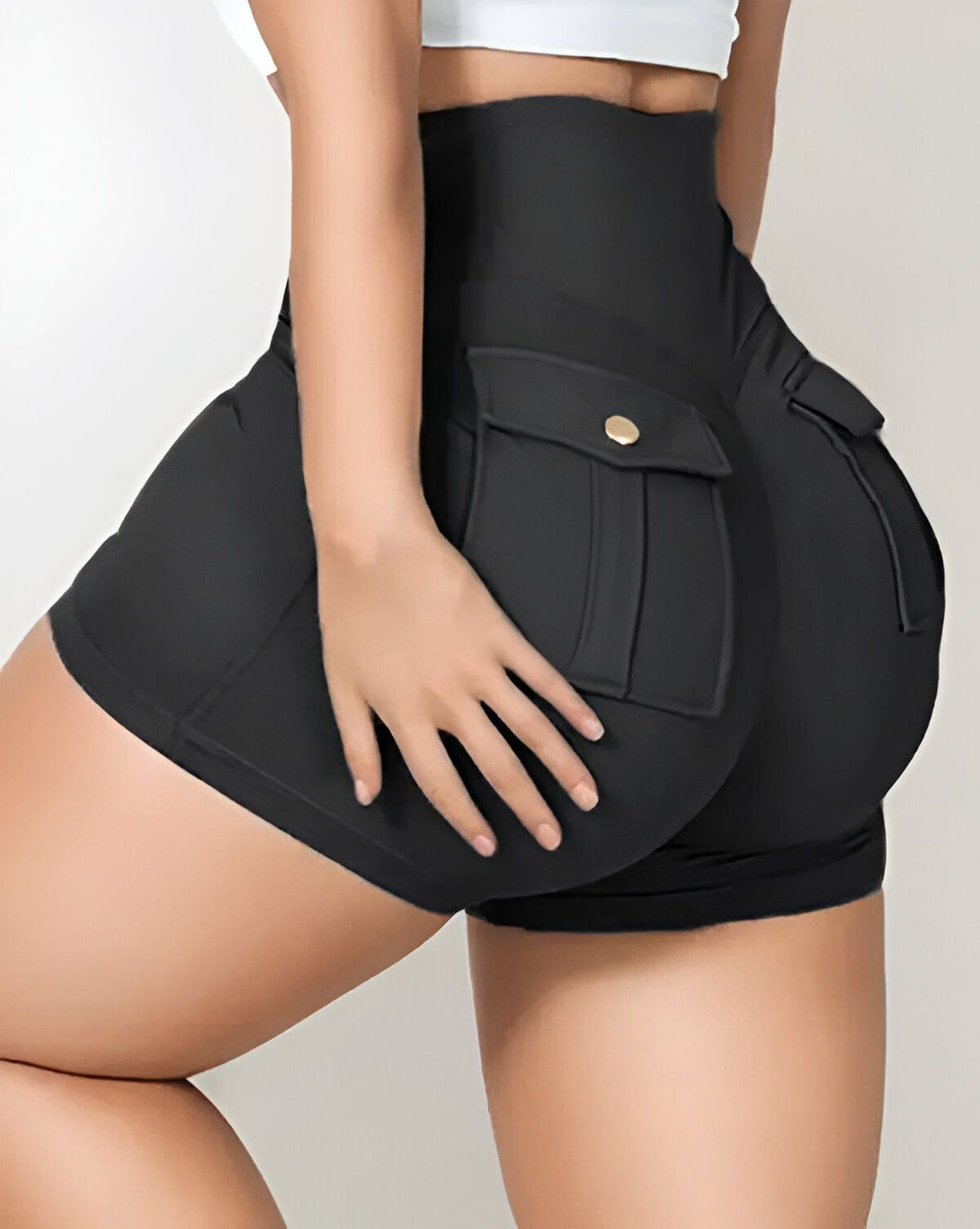 Une femme porte un short moulant noir taille haute avec des poches.