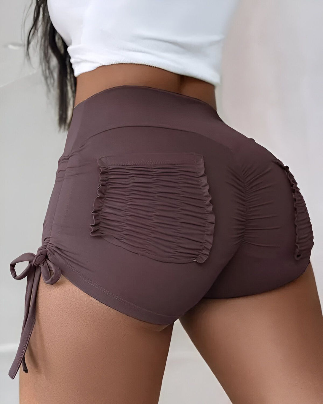 Une femme porte un short marron moulant avec des poches et des cordons de serrage sur les côtés.