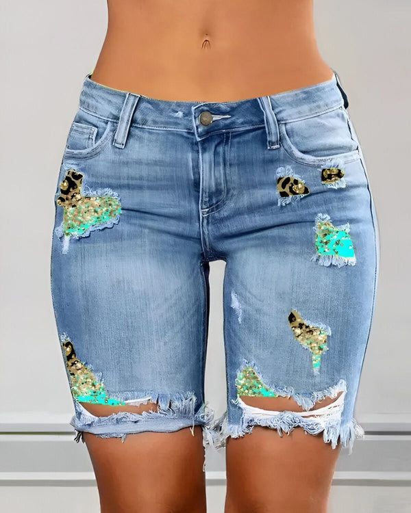 Une image d'un short en jean bleu déchiré avec des paillettes vertes et des motifs léopard.