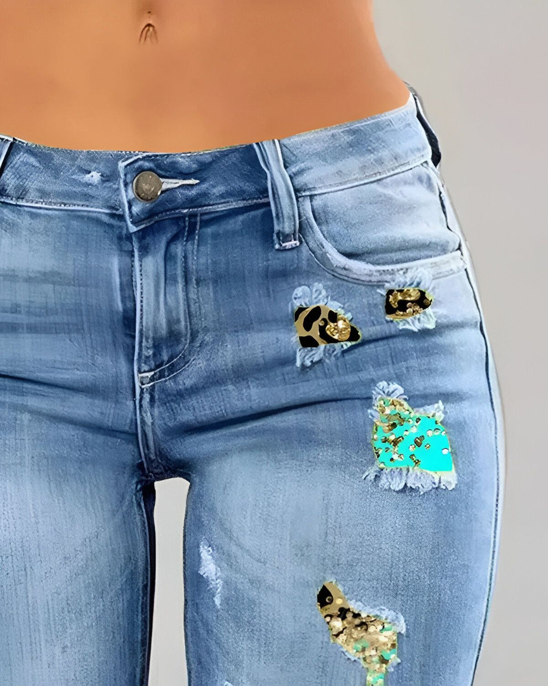 Une image d'un jean bleu déchiré avec des patchs en léopard et en paillettes turquoise.
