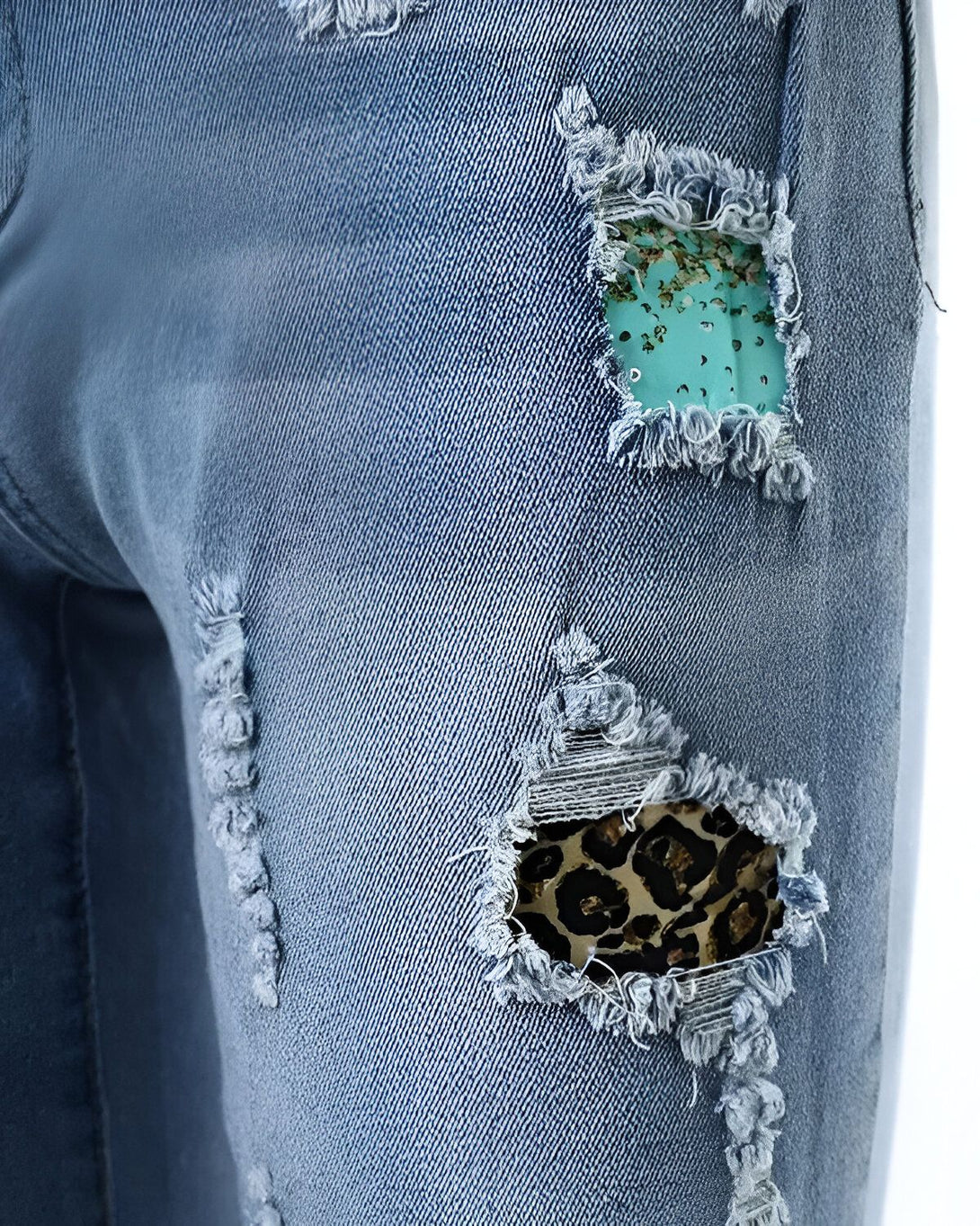 Une image d'un jean bleu déchiré avec des patchs de couleur turquoise et léopard.