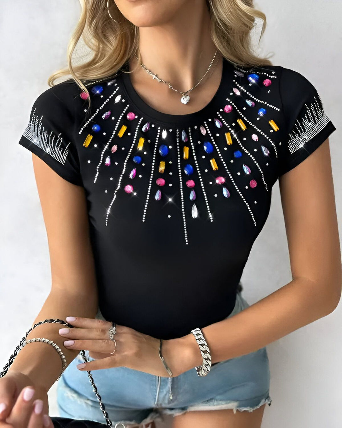 Une femme porte un t-shirt noir à manches courtes avec des pierres précieuses colorées sur le devant.