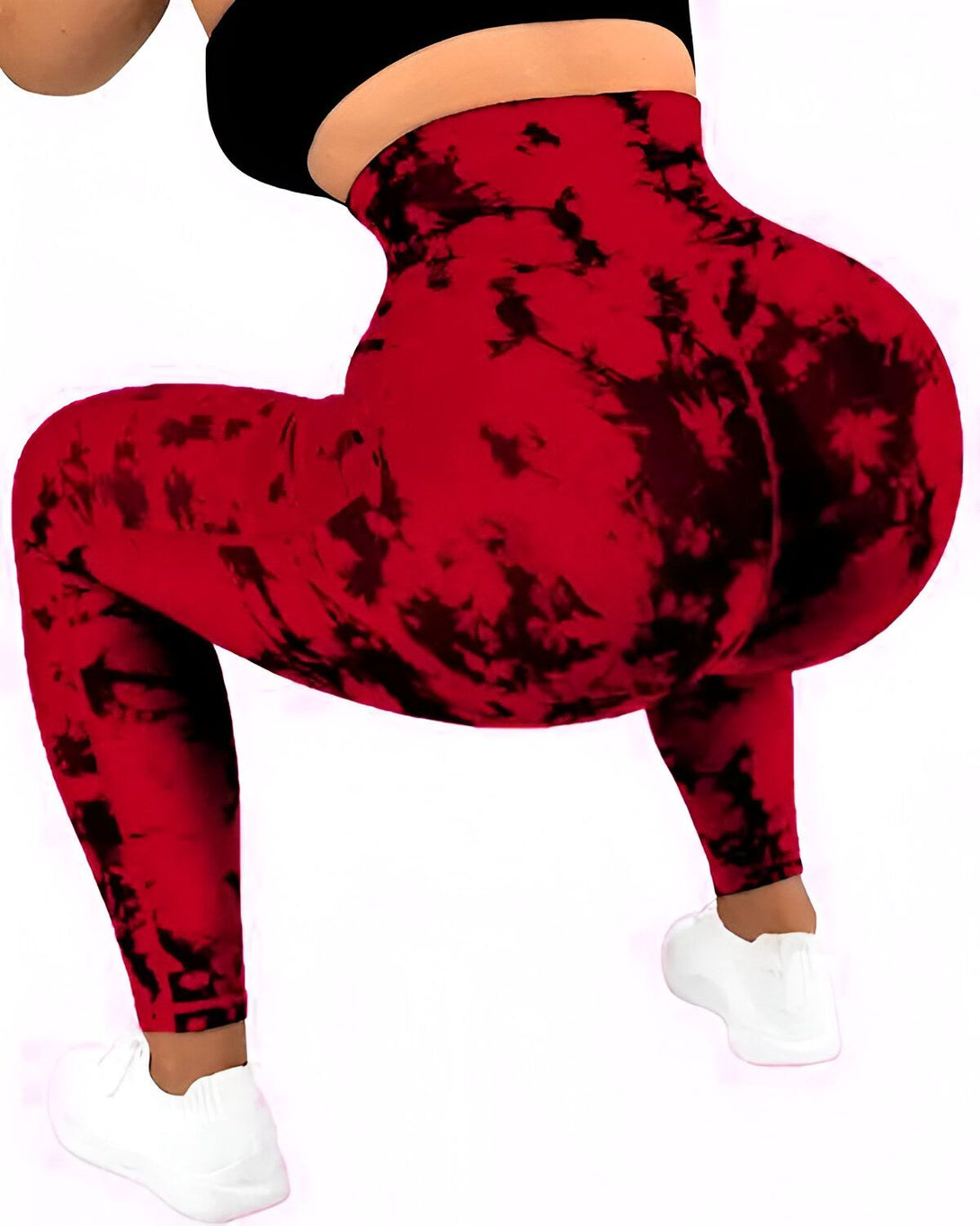 Une femme porte un legging rouge tie-dye avec des baskets blanches.