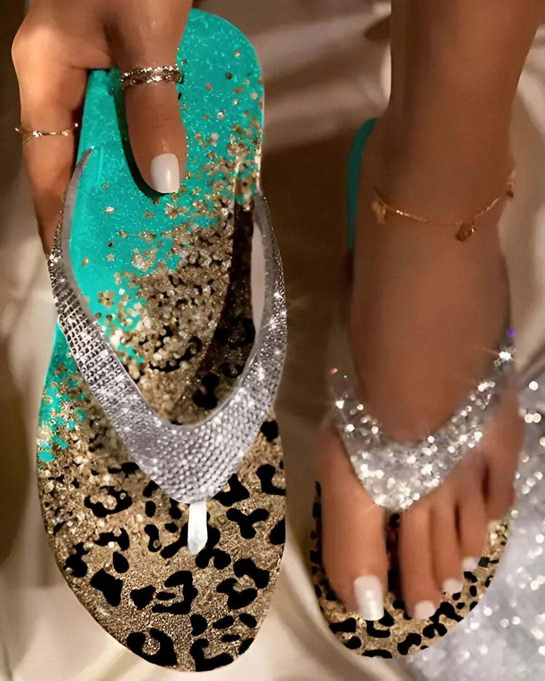 Une femme porte des tongs bleues et dorées à paillettes avec un motif léopard. Les tongs sont ornées de strass argentés.