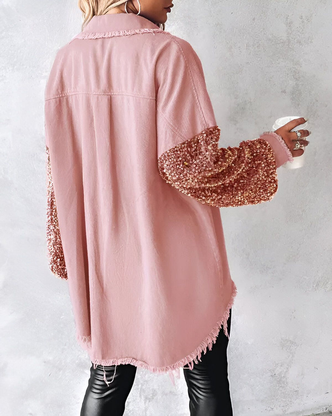 Une femme porte une chemise rose en jean avec des manches à paillettes dorées. Elle est vue de dos.
