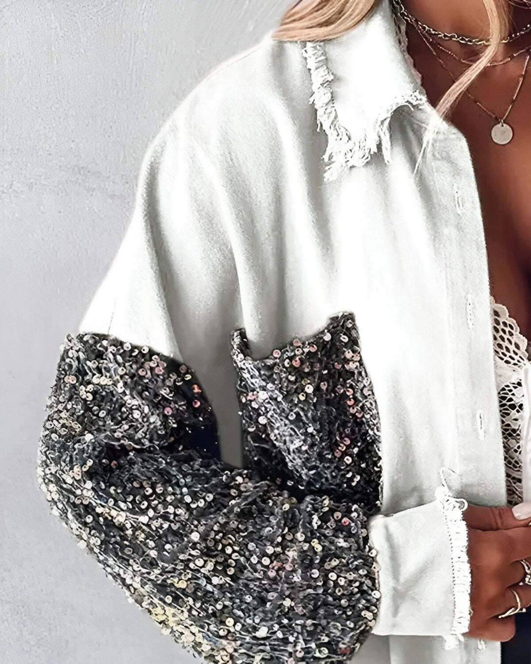 Une veste en jean blanche avec des sequins noirs sur les manches.