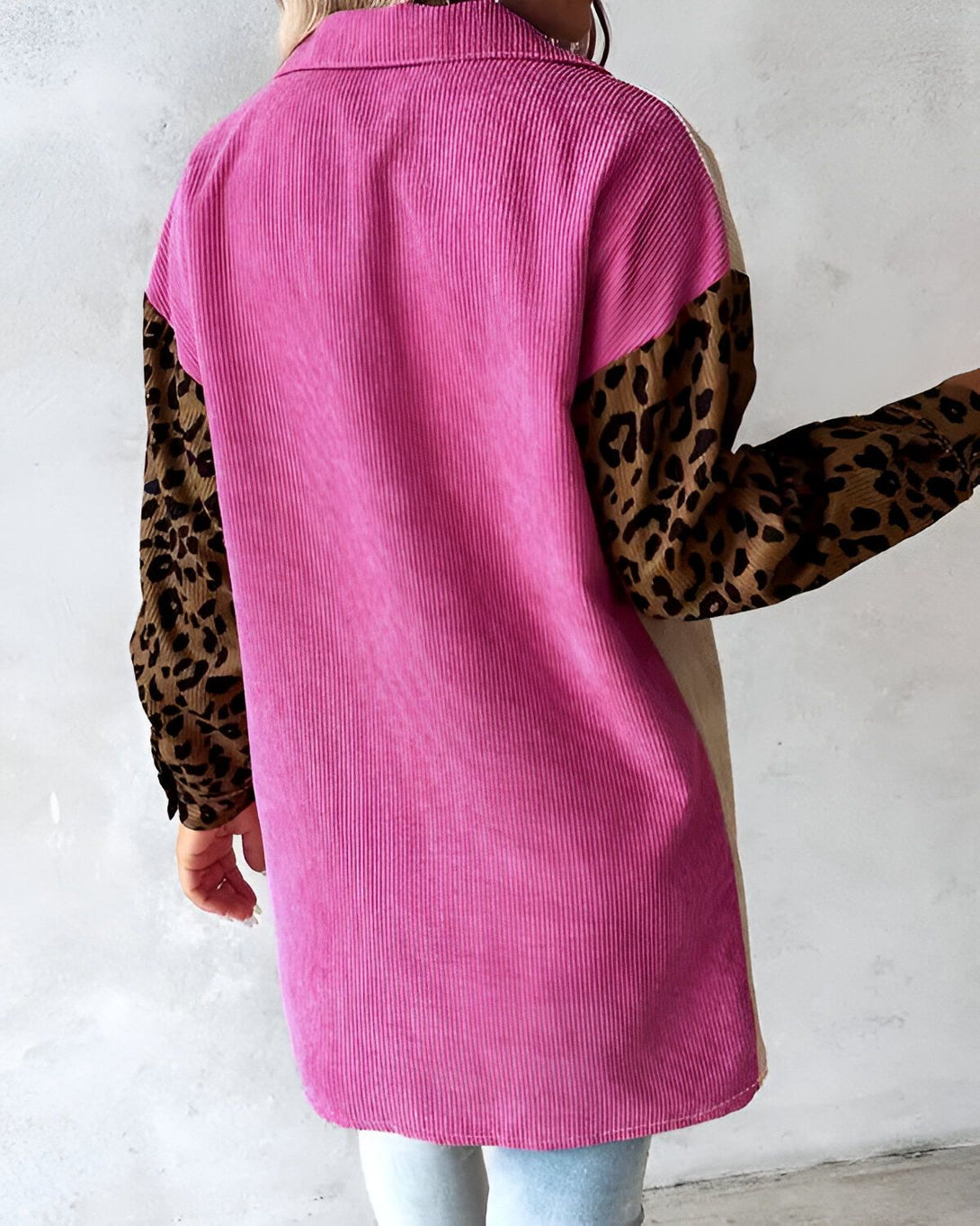 Une chemise rose en velours côtelé avec des manches marrons à motif léopard et des empiècements beiges sur les côtés.