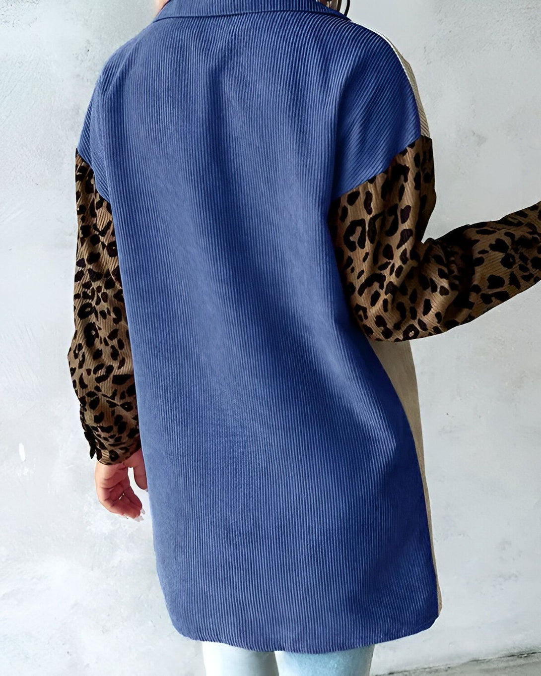 Une image d'une chemise bleue en velours côtelé avec des manches léopard et des empiècements beiges.